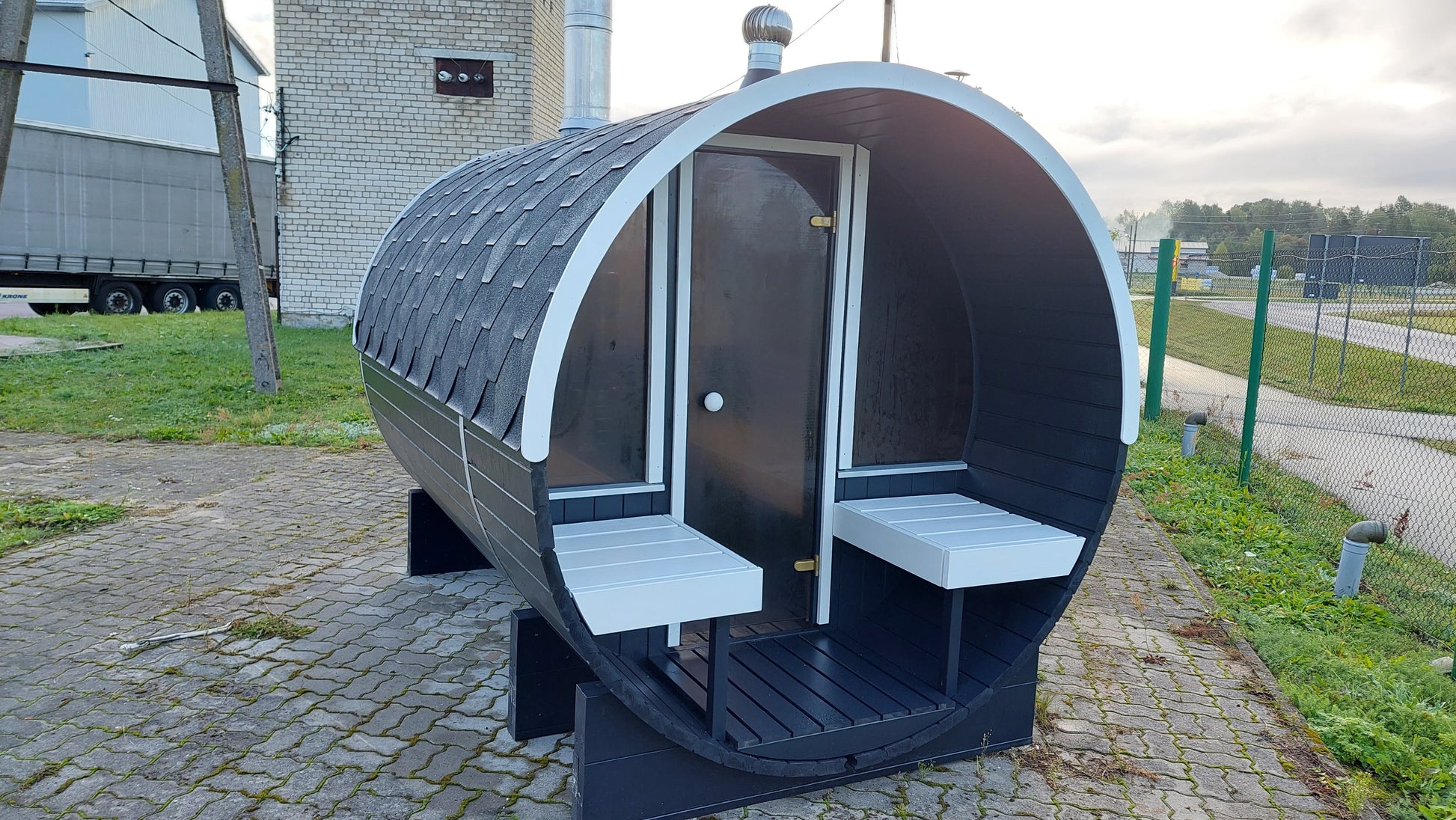 Fasssauna UNO 280 mit Terrasse bietet gemütliche Außensitze für entspannende Saunagänge im eigenen Garten.